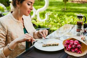 young stylish woman sitting in cafe, eating tasty pie photo