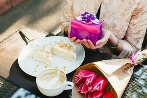 joven elegante mujer sentado en cafetería, comiendo sabroso pastel foto