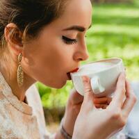 young stylish woman, sitting in cafe, holding drinking cup cappuccino photo