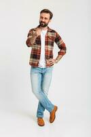 handsome bearded man in hipster outfit dressed in jeans and checkered shirt photo