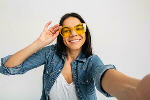 attractive woman dressed jeans and denim shirt wearing yellow sunglasses photo