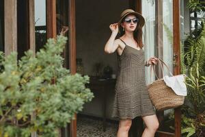 young beautiful stylish woman in resort hotel, wearing trendy dress photo