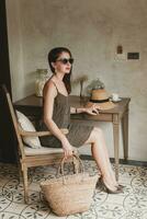 joven hermosa elegante mujer en recurso hotel habitación, sentado a mesa foto