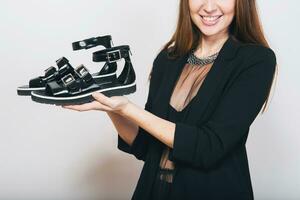 beautiful stylish woman isolated in black suit holding pait of shoes photo