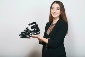 beautiful stylish woman isolated in black suit holding pait of shoes photo