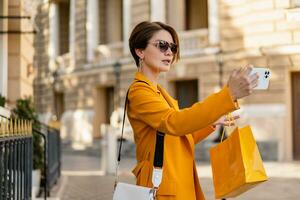 elegante elegante mujer en compras en ciudad calle vistiendo brillante vistoso amarillo traje verano estilo foto