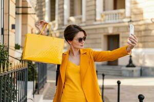 stylish elegant woman on shopping in city street wearing bright colorful yellow suit summer style photo