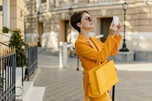 stylish elegant woman on shopping in city street wearing bright colorful yellow suit summer style photo