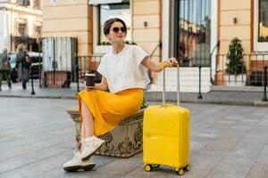 stylish woman traveling with yellow suitcase in Europe photo