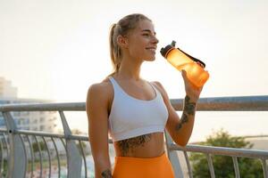 bonito joven sonriente mujer haciendo Deportes en el Mañana en elegante deporte atuendo ropa de deporte, flaco fuerte cuerpo, sano ajuste estilo de vida foto