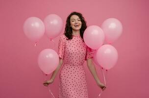 pretty young woman posing isolated on pink studio background with pink air baloons photo