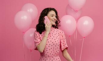 bonito joven mujer posando aislado en rosado estudio antecedentes con rosado aire globos y teléfono inteligente foto