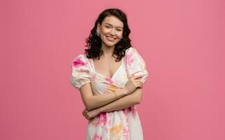 pretty young woman posing isolated on pink studio background in dress photo
