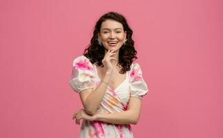 pretty young woman posing isolated on pink studio background in dress photo