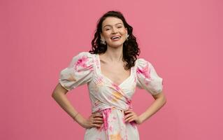 pretty young woman posing isolated on pink studio background in dress photo