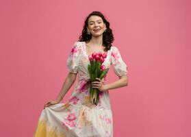 pretty young woman posing isolated on pink studio background with tulips flowers photo