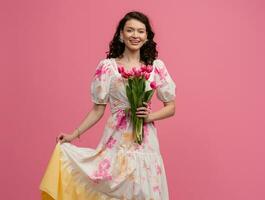 pretty young woman posing isolated on pink studio background with tulips flowers photo