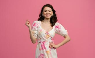 pretty young woman posing isolated on pink studio background in dress photo