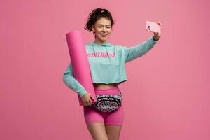 smiling happy beautiful woman in stylish sports outfit posing on pink background isolated in studio photo