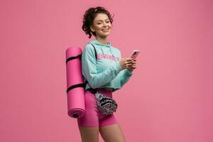 smiling happy beautiful woman in stylish sports outfit posing on pink background isolated in studio photo