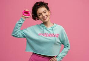 smiling happy beautiful woman in stylish sports outfit doing workout on pink background isolated in studio photo