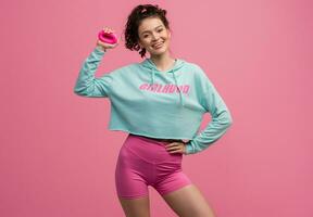 smiling happy beautiful woman in stylish sports outfit doing workout on pink background isolated in studio photo
