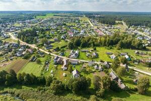 panoramic aerial view of small provincial town or big eco village with wooden houses, gravel road, gardens and orchards photo