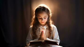 linda niño niña leyendo Biblia libro. Adoración a hogar. foto