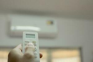 Man's hand is turning on and off the air conditioner because it's hot. photo