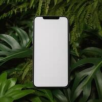white screen smartphone in front of green leaves photo