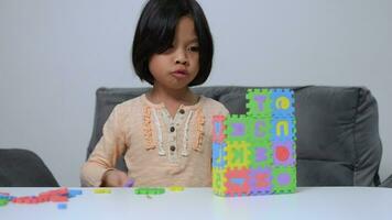 fofa ásia pequeno menina jogando com colorida brinquedo abc quebra-cabeça, crianças jogar com educacional brinquedos às Jardim da infância ou creche. criativo jogando do criança desenvolvimento conceito, criança pequena criança dentro berçário. video