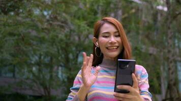 A smiling female tourist talking via text message link on the park in the hotel. Feel happy. text message chat. Close up happy woman text message chatting online on mobile phone outdoor. video