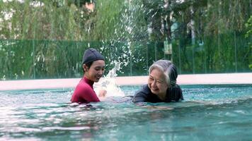 ung tränare portion senior kvinna i aqua aerobics och arbetssätt ut i de slå samman. gammal kvinna och mogna man håller på med aqua aerobics övning i simning slå samman, äldre sporter, och aktiva livsstil begrepp. video