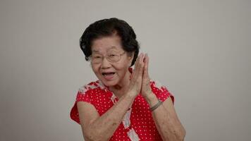 Portrait cheerful smiling Asian senior woman wear glasses grey hair over isolated white background and excited doing winner, clap hands, thumb up, smiling celebration for success. video