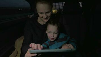 Mother and son playing with touch pad during night car ride video