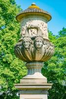 Dresden, Germany -  Statue of a Cup with women faces in the citizen meadow park called Burgerwiese. Cityscape of the downtown at sunny Spring day and blue sky. photo