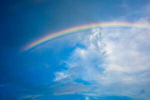 Beautiful multi-colored rainbow after rain on the blue sky and white clouds. photo