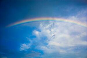 Beautiful multi-colored rainbow after rain on the blue sky and white clouds. photo