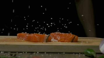 Professional chef salting red fish steak. Slow motion close up video