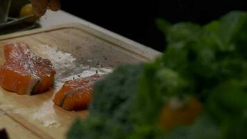 Professional chef salting red fish steak. Slow motion close up video