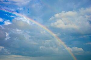 Beautiful multi-colored rainbow after rain on blue sky and white clouds In the middle of a village in a community in Thailand photo