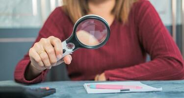 woman doing work and using a magnifying glass to look at data Suitable for making infographics. photo