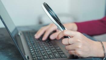 woman doing work and using a magnifying glass to look at data Suitable for making infographics. photo