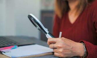 woman doing work and using a magnifying glass to look at data Suitable for making infographics. photo