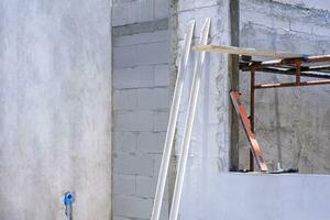 Perspective side view of 2 long wooden trowels with various work tools and scaffolding inside of window frame in house construction site area photo