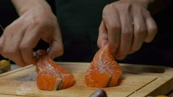profissional chefe de cozinha prepara vermelho peixe bife para fritando. fechar acima lento movimento. video