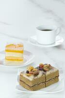 Coffee cake and orange soft fudge cake with black coffee on white marble table in vertical frame, selective focus photo