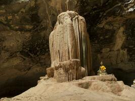 There are stalactites in the cave, there is a Buddha image inventing the conjunction on the side. photo