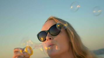 joven mujer en Gafas de sol soplo jabón burbujas video