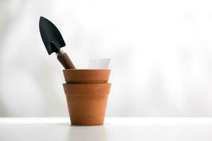 A clay pot and planting equipment on a white wooden table. photo